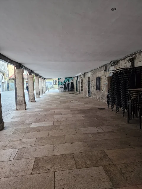 Perspectiva bajo los soportales de piedra con columnas cuadradas