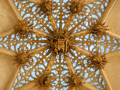 Detalle de tracería gótica flamígera dorada en forma de estrella de ocho puntas en la linterna de la capilla
