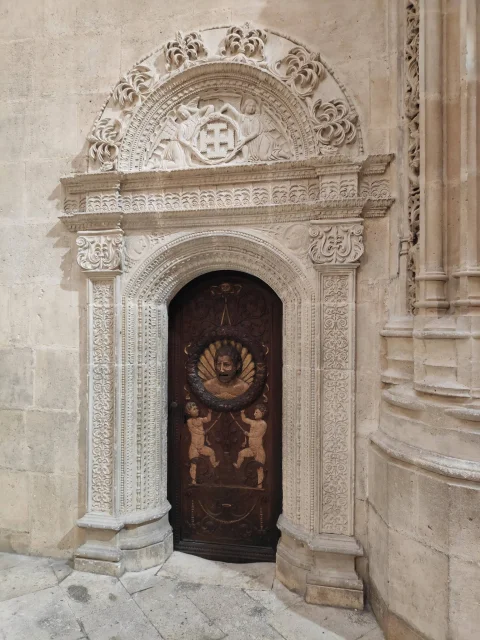 Puerta de la sacristía con relieves de atlantes y máscara central enmarcada por portada renacentista