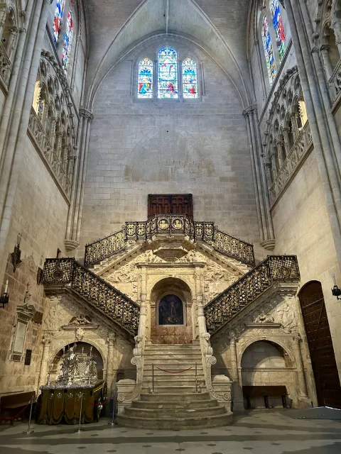 Vista completa del transepto gótico con la Escalera Dorada renacentista y vidrieras altas en Burgos