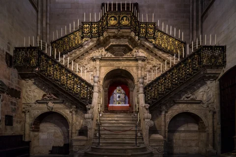 Vista frontal de la Escalera Dorada iluminada con relicario expuesto en la hornacina central