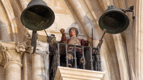 Autómata del Martinillo en un balcón metálico entre dos campanas de bronce en la Catedral de Burgos