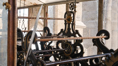 Detalle de la maquinaria de engranajes y péndulo del reloj histórico en su vitrina