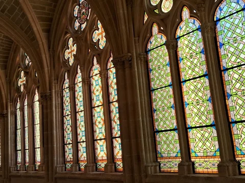 Ventanales góticos cerrados con vidrieras geométricas y tracerías caladas en la galería del Claustro Alto