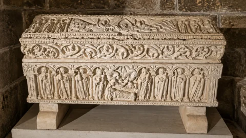 Sepulcro románico de doña Godo con relieves esculpidos de figuras y cubierta a dos aguas en el Claustro Bajo