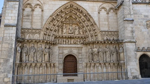 Fachada gótica con portal renacentista enmarcado por esculturas monumentales de apóstoles y tímpano historiado