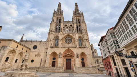 Perspectiva de la fachada gótica de Santa María flanqueada por altas torres con agujas y plaza empedrada