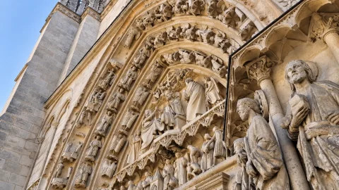 Primer plano en ángulo de relieves góticos con Cristo Juez, la Virgen, san Juan y figuras en las arquivoltas