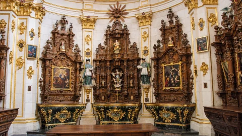 Conjunto de tres retablos de nogal tallado sobre bases marmóreas verdes con figuras de santos y lienzos