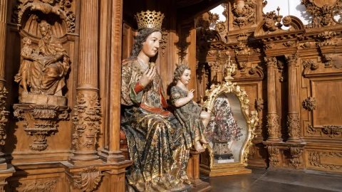 Escultura gótica policromada de la Virgen de Oca con el Niño junto a los relieves de madera tallada del retablo