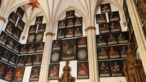 Paredes de la capilla gótica con hileras ordenadas de retratos pictóricos de prelados burgaleses y retablo de madera