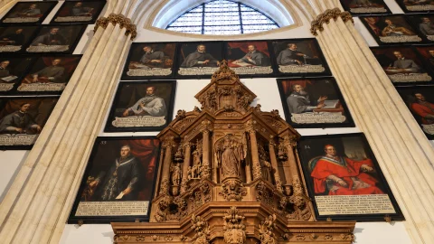 Remate superior del retablo de madera tallada de Santa Catalina enmarcado por pinturas episcopales