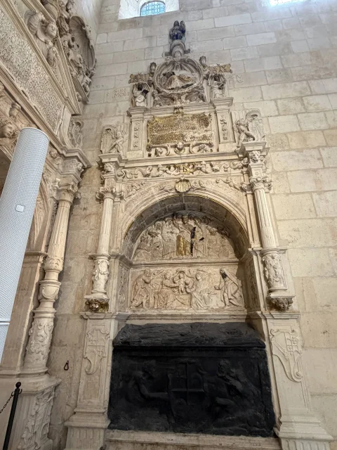 Sepulcro monumental renacentista adosado con arcosolio, escenas bíblicas talladas y urna funeraria de pizarra