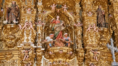Detalle de escultura policromada de santa Tecla en la hoguera rodeada de exuberante talla dorada y angelotes