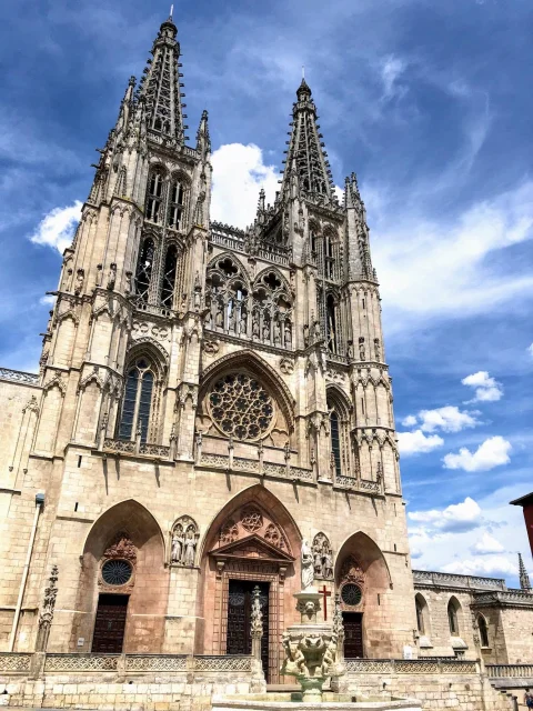 Torres góticas de la Catedral de Burgos y plaza de Santa María bajo un cielo cubierto de nubes