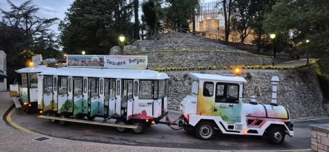 Tren turístico blanco en la curva al pie del Castillo de Burgos