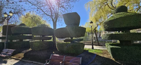 Conjunto de tejos recortados en formas geométricas escalonadas con banco de madera y farolas clásicas