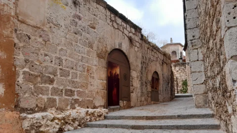 Entrada empedrada con arcos y pintura urbana en la Calle Embajadores