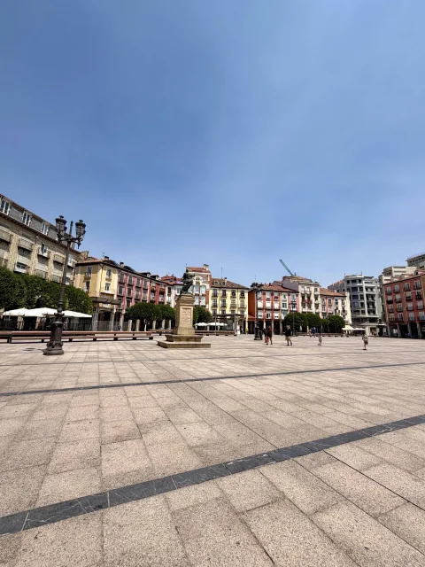 Perspectiva gran angular del suelo de losas de piedra de una plaza rodeada por fachadas tradicionales