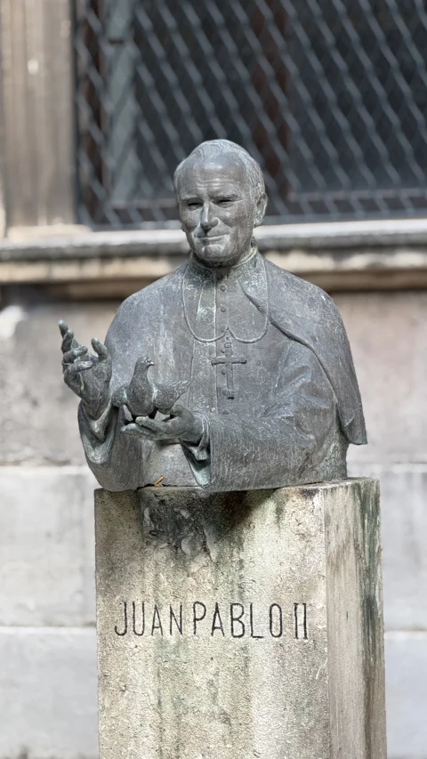 Detalle en bronce de la escultura de Juan Pablo II sosteniendo la paloma sobre su pedestal de piedra