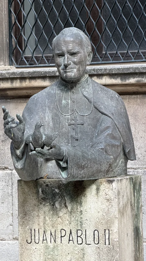 Primer plano del busto en bronce del Papa San Juan Pablo II con la paloma de la paz en la Facultad de Teología de Burgos