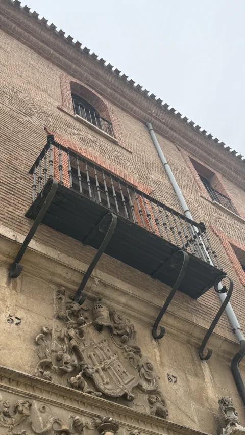 Detalle de balcón de hierro y escudo heráldico