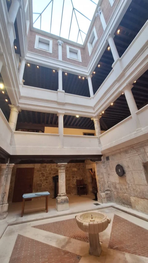 Perspectiva vertical del patio interior mostrando las galerías en varios niveles y la claraboya acristalada superior