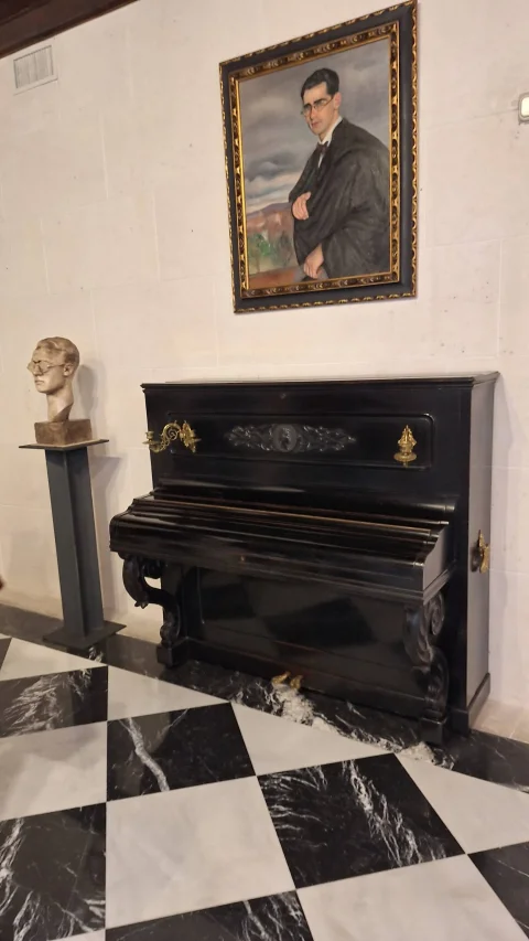 Piano vertical clásico y retrato al óleo sobre suelo de damero