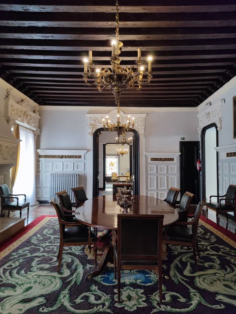 Salón de banquetes con gran mesa ovalada y alfombra estampada