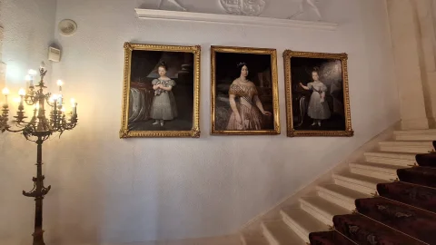 Tres retratos al óleo de época con marcos dorados colgados en la pared