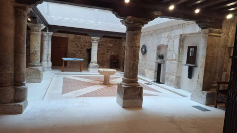 Vista en ángulo de las arcadas y columnas de piedra de la planta baja que rodean el patio central