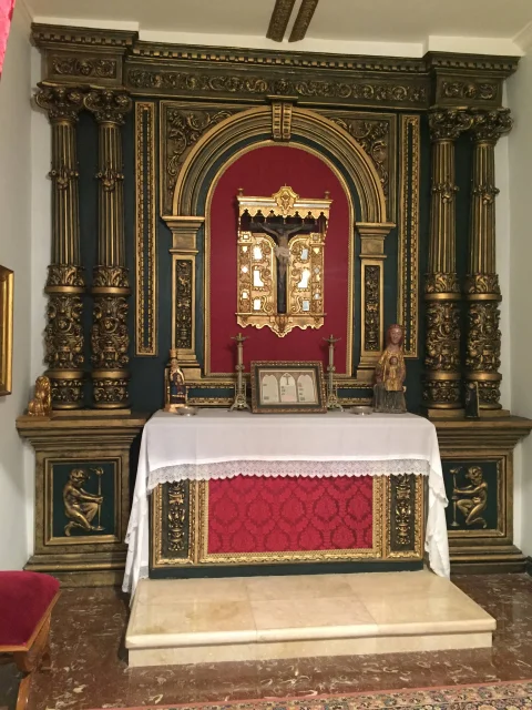 Vista frontal del retablo barroco con columnas salomónicas doradas, hornacina central con crucifijo