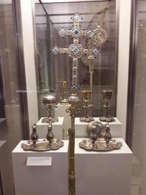 Conjunto litúrgico pontifical con cruz procesional de plata, cálices, vinajeras y palmatoria