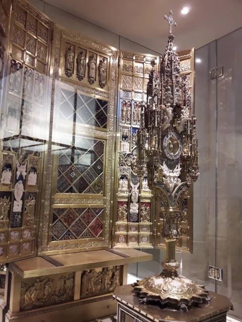 Custodia de torre en plata repujada y esmaltes junto a retablo relicario con placas de marfil y orfebrería