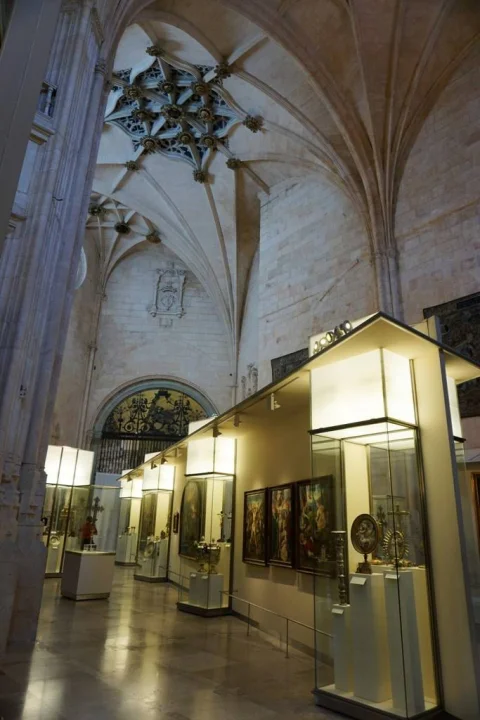 Perspectiva general de la sala museística con módulos expositivos iluminados bajo bóvedas de crucería estrellada