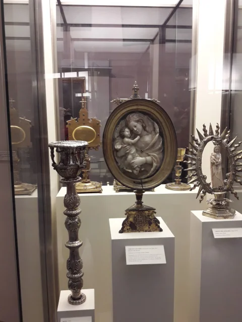 Relicario oval con relieve de la Virgen con el Niño, candelabro de plata labrada y viril