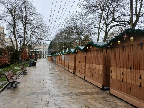 Casetas navideñas de madera alineadas en el paseo empedrado con arbolado invernal