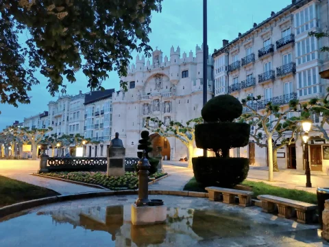 Estanque polilobulado con surtidor y busto ante la fachada iluminada del Arco de Santa María