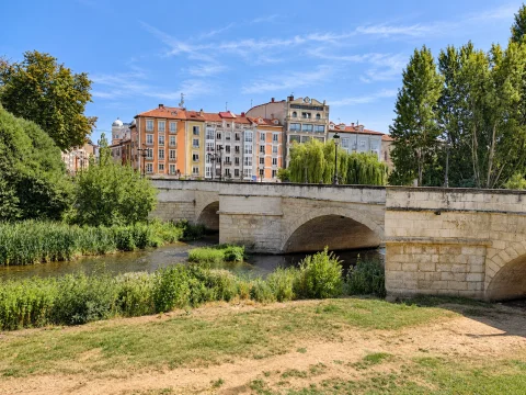 Arcadas de medio punto de sillería sobre el río Arlanzón con el frente de edificios coloridos del Espoloncillo