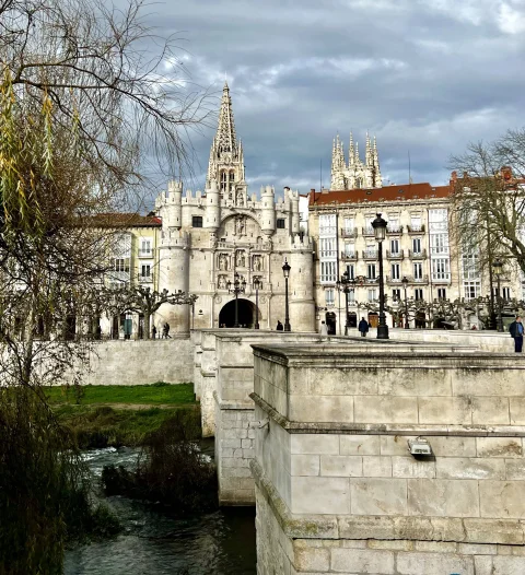 Estructura de sillería del puente sobre el cauce del río con el arco torreado y la aguja gótica de la catedral
