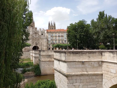Vista angular de los tajamares de sillería del Puente de Santa María con el arco monumental y la catedral de fondo