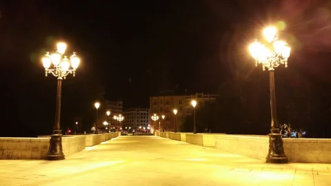 Vista nocturna de la calzada peatonal del Puente de Santa María iluminada por farolas ornamentales
