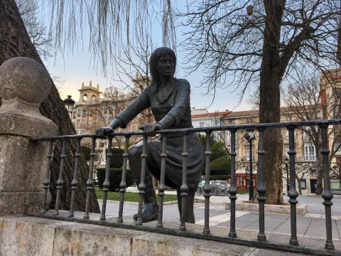 Vista frontal de Mujer mirando al río Arlanzón asomada al río con la arboleda y fachadas burgalesas de fondo