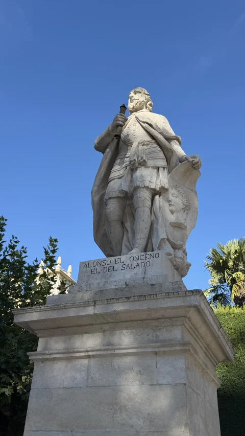 Estatua de piedra blanca del rey Alfonso XI sosteniendo un cetro sobre alto pedestal