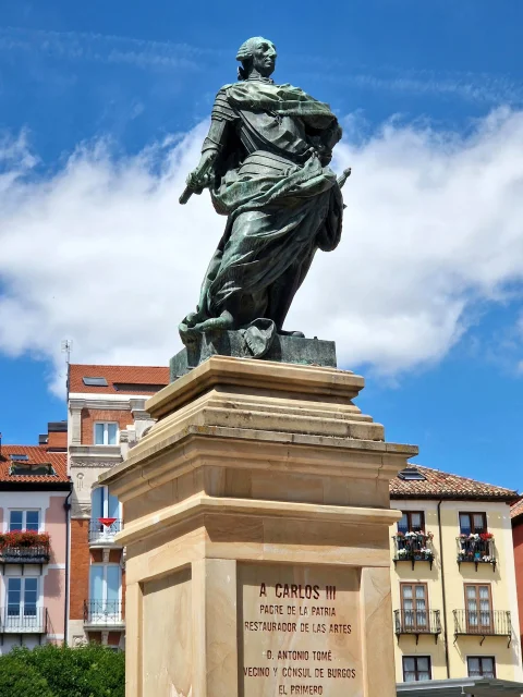 Estatua de bronce de Carlos III sobre un alto pedestal de piedra grabado