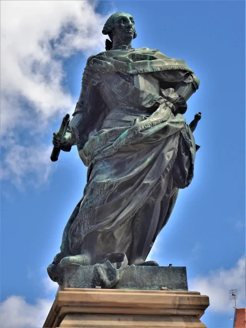 Plano contrapicado de la escultura de bronce de Carlos III vistiendo capa y sosteniendo un cetro