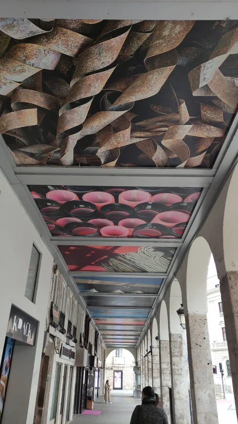 Paneles artísticos de virutas metálicas e hilos en el techo del soportal