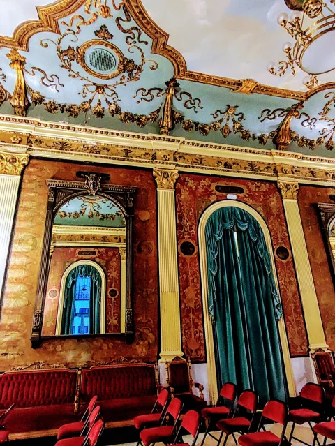 Decoración palaciega del Salón Rojo del Teatro Principal con molduras doradas, tapices y cortinajes
