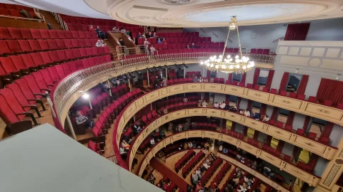 Perspectiva general en herradura de la sala del Teatro Principal con palcos, butacas rojas y lámpara de araña