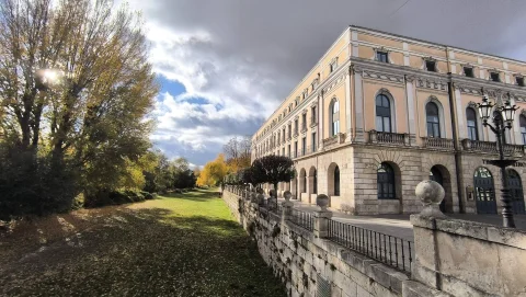 Perspectiva del muro de sillería ribereño con esferas de piedra y arboleda otoñal ante el Teatro Principal